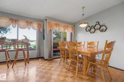 Dining area featuring a parquet wood-finish floor, a large window, and a glass-paneled sliding door - 