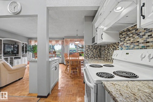 Kitchen featuring white cabinetry, granite-finish countertops, and a mosaic tile backsplash - 10242 161 Street, Edmonton, AB 
