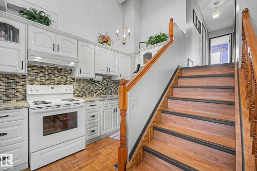 Kitchen featuring white cabinetry with dark hardware, a tile backsplash, and light-toned countertops - 10242 161 Street, Edmonton, AB 
