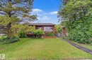 Single-story property with a brick exterior, large front lawn, mature trees, and a concrete pathway leading to the entrance - 10242 161 Street, Edmonton, AB 
