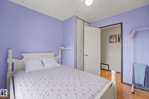Bedroom featuring wood-finish flooring, a white ceiling fan light fixture, and a built-in closet with sliding doors - 10242 161 Street, Edmonton, AB 