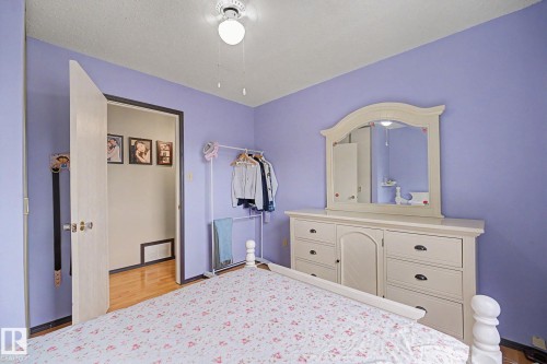 Bedroom featuring light purple walls, wood-finish flooring, a ceiling fan with integrated lighting, and a doorway leading to a separate area - 10242 161 Street, Edmonton, AB 