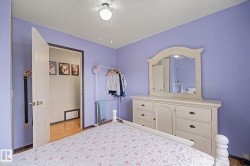 Bedroom featuring light purple walls, wood-finish flooring, a ceiling fan with integrated lighting, and a doorway leading to a separate area - 
