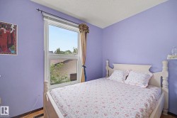Room featuring a double-hung window, light purple walls, and wood-finish flooring - 