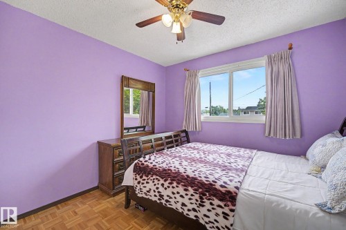 Room featuring parquet wood flooring, a ceiling fan with integrated lighting, and a large window with white trim - 10242 161 Street, Edmonton, AB 