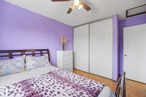 Room featuring wood-finish flooring, a ceiling fan, sliding closet doors, and a solid door - 10242 161 Street, Edmonton, AB 