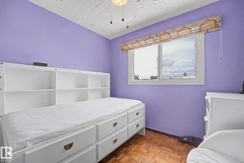 Room featuring light purple wall paint, wood-finish parquet flooring, and a white framed window with a patterned Roman shade - 10242 161 Street, Edmonton, AB 