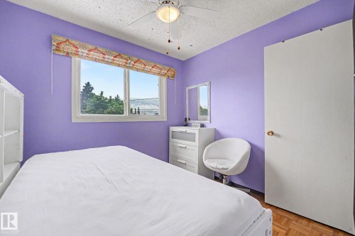Bedroom featuring a single window with a patterned Roman shade, wood-finish flooring, a ceiling fan with integrated lighting, and a white interior door - 10242 161 Street, Edmonton, AB 