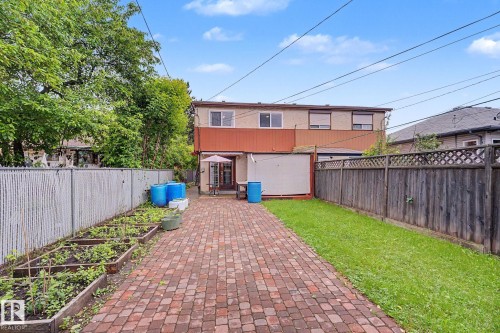Expansive paver patio extending from the property, framed by a manicured lawn and garden beds - 10242 161 Street, Edmonton, AB 