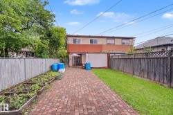 Expansive paver patio extending from the property, framed by a manicured lawn and garden beds - 