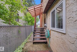 Exterior stucco finish with a modern white-framed window, covered porch stairs, and a chain-link fence featuring privacy slats - 