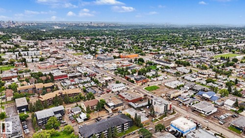 Aerial perspective showcasing a diverse urban landscape with commercial and residential structures, extensive tree canopies, and a distant city skyline - 10242 161 Street, Edmonton, AB 