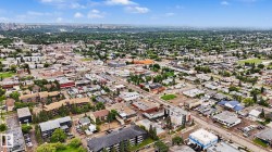 Aerial perspective showcasing a diverse urban landscape with commercial and residential structures, extensive tree canopies, and a distant city skyline - 