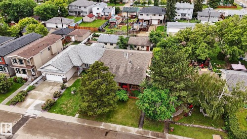 Well-maintained residential property featuring a large front yard with mature trees, a paved driveway, and an attached two-car garage - 10242 161 Street, Edmonton, AB 