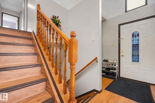 Staircase featuring wood-finish treads and risers with dark trim, complemented by a natural wood balustrade and handrail - 10242 161 Street, Edmonton, AB 