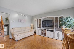 Parquet wood-finish flooring throughout, featuring a built-in entertainment unit with glass-front display cabinets and integrated storage - 