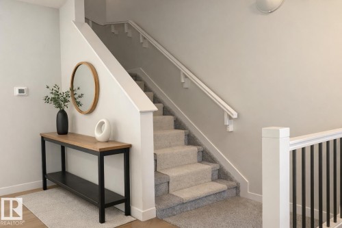 Virtually staged. Carpeted staircase featuring a white railing system, light neutral wall paint, and a built-in wall sconce - 9952 227 Street, Edmonton, AB 