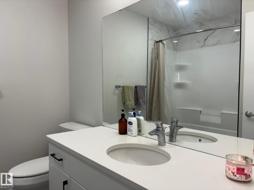 Bathroom featuring a white vanity with integrated sink, chrome faucet, and black hardware - 9952 227 Street, Edmonton, AB 