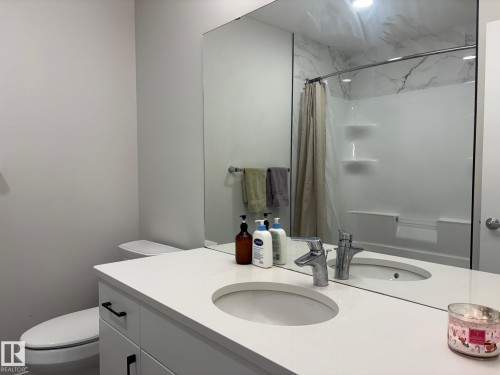 Bathroom featuring a white vanity with an integrated sink, polished chrome faucet, and a large wall-mounted mirror - 9952 227 Street, Edmonton, AB 