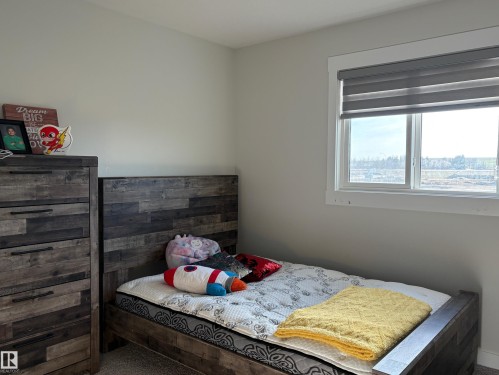 Light-filled room featuring a large window with white trim, gray roller blinds, and neutral wall paint - 9952 227 Street, Edmonton, AB 