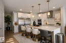 Virtually staged. Gourmet kitchen featuring a large island with seating, stainless steel appliances, white cabinetry, and subway tile backsplash - 9952 227 Street, Edmonton, AB 