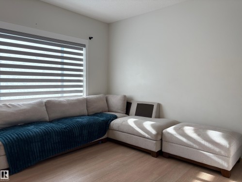 Wide window with horizontal blinds, light wood-finish flooring, and neutral wall paint - 9952 227 Street, Edmonton, AB 