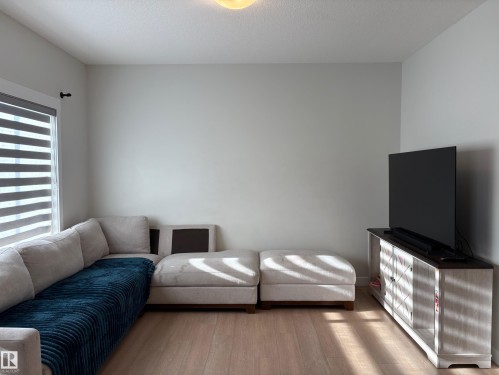 Light wood-finish flooring throughout, complemented by light gray wall paint - 9952 227 Street, Edmonton, AB 