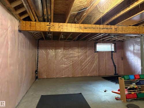 Unfinished basement with concrete flooring, exposed wooden joists, and a window with horizontal blinds - 9952 227 Street, Edmonton, AB 