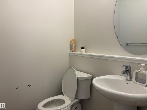 Pedestal sink with chrome faucet, circular wall mirror, and towel bar - 9952 227 Street, Edmonton, AB 