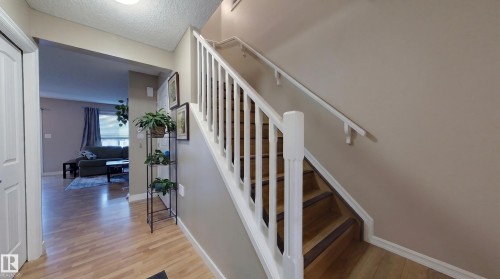 Wood-finish flooring throughout the entry, leading to a staircase with white balusters and wood treads - 21207 90Ave, Edmonton, AB 