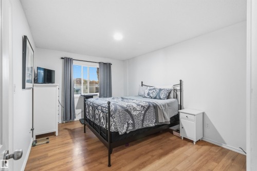 Bedroom featuring wood-finish flooring, a multi-pane window, and white walls - 21207 90Ave, Edmonton, AB 