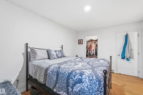 Bedroom featuring hardwood-style flooring, white walls, and a built-in closet with shelving and hanging space - 21207 90Ave, Edmonton, AB 