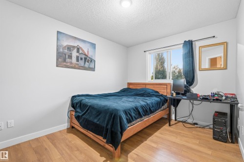 Bedroom featuring wood-finish flooring, a double-pane window, and white trim - 21207 90Ave, Edmonton, AB 