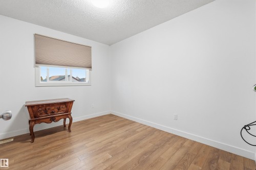 Bright room featuring wood-finish flooring and a white window frame with a pleated shade - 21207 90Ave, Edmonton, AB 