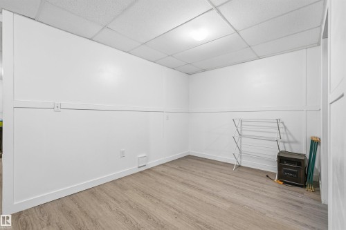 Light wood-finish flooring complements crisp white walls with paneling - 21207 90Ave, Edmonton, AB 