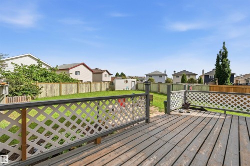 Expansive backyard featuring a wood-finish deck with lattice railing, a manicured lawn, and a storage shed - 21207 90Ave, Edmonton, AB 