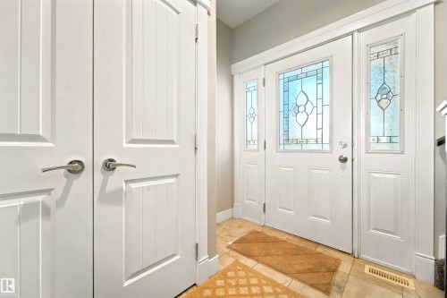 Entryway featuring a white paneled door with decorative stained glass, flanked by two matching sidelights - 5110 Rue Eaglemont, Beaumont, AB 
