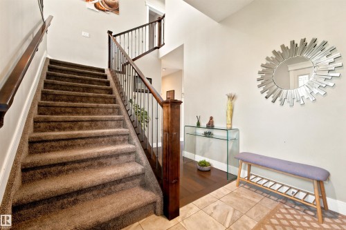Carpeted staircase featuring dark wood newel posts and handrails with metal balusters - 5110 Rue Eaglemont, Beaumont, AB 