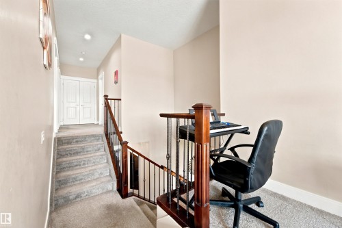Carpeted staircase featuring wood newel posts and metal balusters - 5110 Rue Eaglemont, Beaumont, AB 