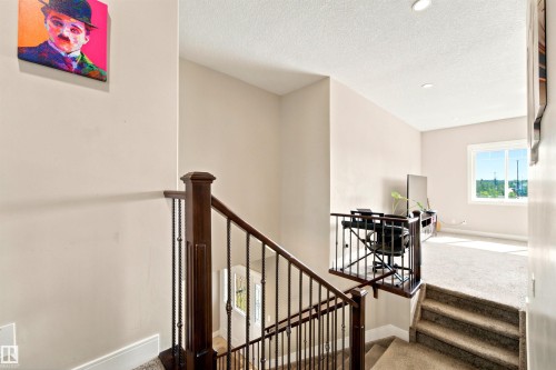 Carpeted staircase with dark wood newel post and wrought iron balusters - 5110 Rue Eaglemont, Beaumont, AB 