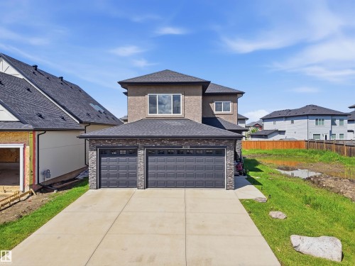 Contemporary stucco and stone-clad residence featuring a spacious two-car garage with panel doors - 5110 Rue Eaglemont, Beaumont, AB 