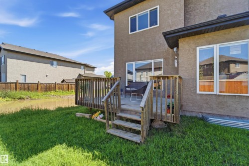 Rear exterior featuring a wooden deck with railing, a grass lawn, and a wooden privacy fence - 5110 Rue Eaglemont, Beaumont, AB 