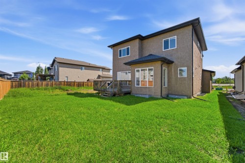 Spacious backyard featuring a large green lawn, a multi-level wood deck, and a privacy fence - 5110 Rue Eaglemont, Beaumont, AB 