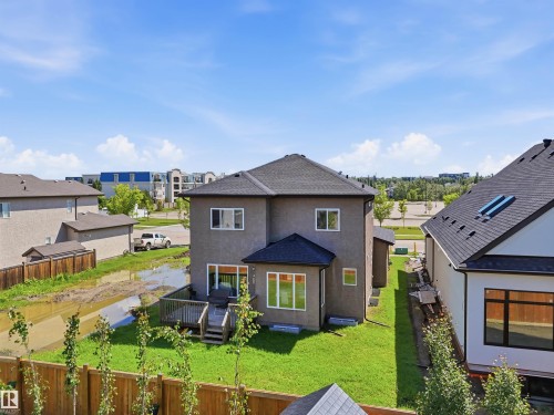 Rear exterior featuring a wood deck, manicured lawn, and dark shingle roof - 5110 Rue Eaglemont, Beaumont, AB 