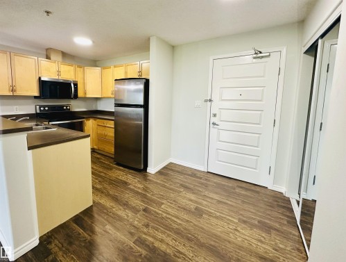 Kitchen and entryway featuring wood-finish flooring - 318 646 Mcallister Loop, Edmonton, AB 