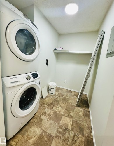 Dedicated laundry area featuring patterned tile flooring, a built-in overhead shelf, and a ceiling-mounted light fixture - 318 646 Mcallister Loop, Edmonton, AB 