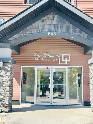 Welcoming building entrance featuring stacked stone pillars, wood-look siding, and a prominent "The Element At MacEwan" sign - 318 646 Mcallister Loop, Edmonton, AB 