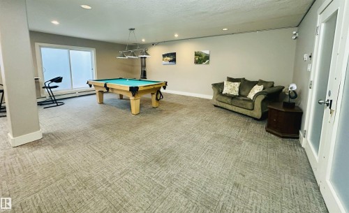 Recreational room featuring a pool table with a multi-light fixture, light-colored walls, and textured carpet flooring - 318 646 Mcallister Loop, Edmonton, AB 