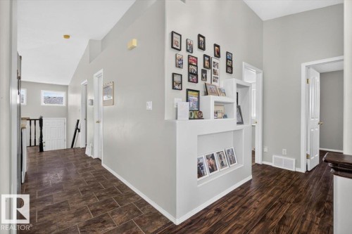 Hallway featuring wood-finish flooring, light grey walls, and a built-in display niche with shelving - 3907 33 Street, Edmonton, AB 