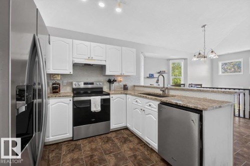 Kitchen featuring white cabinetry, stainless steel appliances, granite countertops, a tile backsplash, and tile flooring - 3907 33 Street, Edmonton, AB 